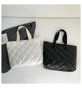 Détail de grands sacs fourre-tout matelassés en nylon brillant noir et blanc perle