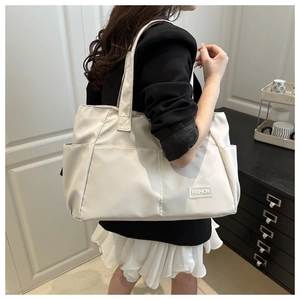 Detail of a beige nylon tote bag with multi-pocket design and 'FASHION' label