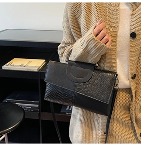 Detail of black crocodile texture leather bag with metal handle in a lifestyle setting