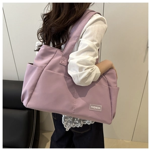 Detail view of large lavender nylon tote bag with side pocket and fashion label patch