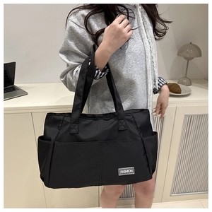 Practical black nylon tote bag worn by a model in a stylish city commuter scene