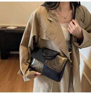 Detail of contrast snake-print leather panel and circular handle on crossbody bag