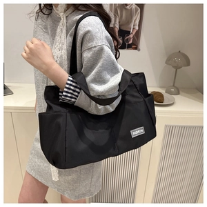 Detailed side view of black nylon tote bag featuring a Fashion label and side pocket