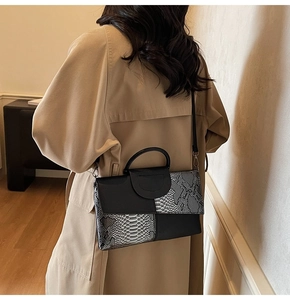 Détail d'un sac à main patchwork à motif serpent porté sur un mannequin en trench