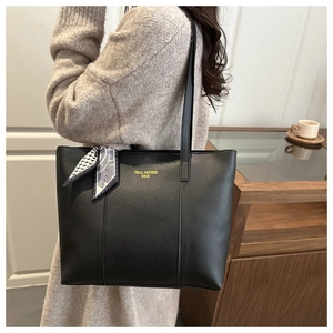 Detail of a large black tote bag with a geometric printed silk scarf on the handle
