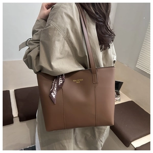 Brown tote bag detail with decorative silk scarf and metallic logo for daily commute