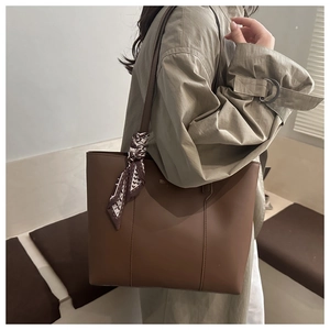 Brown leather tote bag with geometric scarf and gold logo on a trench coat model