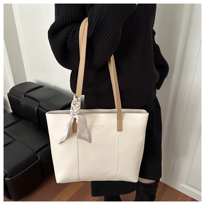 Detail of large cream tote bag with contrast tan handles and decorative silk scarf