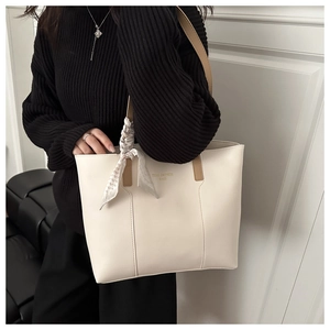 Close-up of large cream tote bag with brown straps and a stylish decorative scarf
