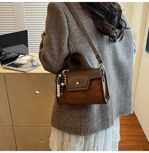 Detail of dark brown retro crossbody bag featuring unique wooden bead charms and metal buckle