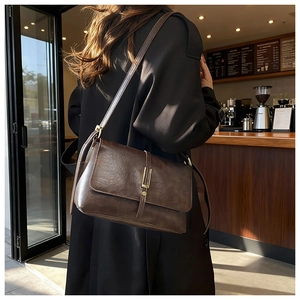 Detail of dark brown vintage oil wax leather bag with golden hardware in a cafe setting
