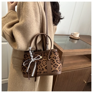 Close-up of leopard print crossbody bag with a bow accent on a camel wool coat