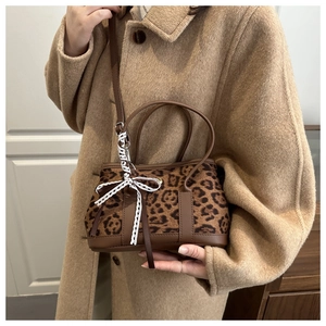Close-up of leopard print handbag with brown leather handles and decorative white lace ribbon