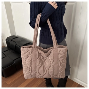 Close-up of pink quilted puffer tote bag featuring wavy stitching and padded straps