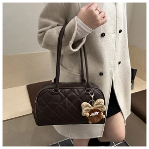 Close-up of quilted coffee brown bowling bag with a cute plush monster charm
