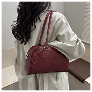 Detail of burgundy quilted tote bag showing fine stitching and shoulder strap on model