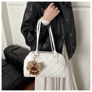 Detail of white quilted handbag with diamond pattern and a brown plush monster charm