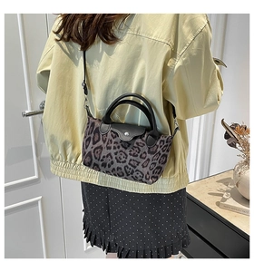 Detailed view of leopard print dumpling bag featuring black leather flap and silver buckle