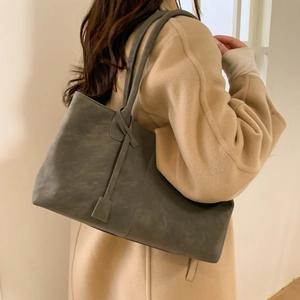 Winter charcoal grey matte leather tote bag worn with a beige coat for a minimalist look
