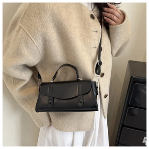 Detail of black faux leather underarm bag with buckle straps and adjustable strap