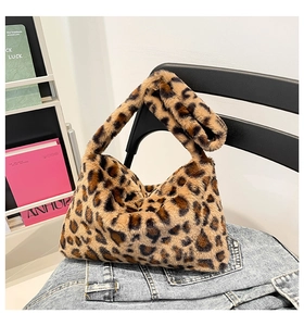 Detail of soft leopard print faux fur shoulder bag placed on blue denim fabric