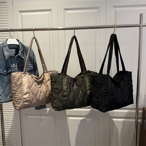 Minimalist quilted puffer tote bags in gold, olive green and black hanging on a rack