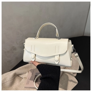 Detail of minimalist beige top-handle crossbody bag with refined envelope flap and stitching