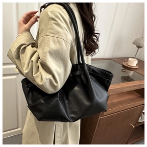 Détail d'un grand sac cabas plissé en cuir noir porté à l'épaule pour un style décontracté