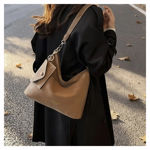 Detailed close-up of brown litchi grain leather bucket bag with fashion gold lettering