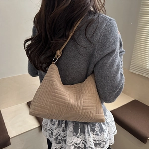 Khaki quilted shoulder bag with moon silhouette and knotted strap worn by a model