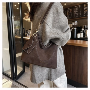 Detail of dark brown leather tote bag with lychee texture and matching small pouch