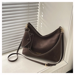 Detail of a brown suede hobo bag with white contrast stitching and a small coin purse