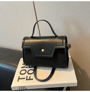 Detail of black leather baguette bag with gold buckle on white fashion books