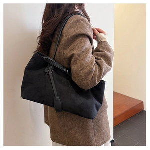 Detail view of large black suede tote bag showing texture and size on a model shoulder