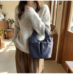 Detail of navy blue nylon tote bag with functional front pockets and sturdy handles