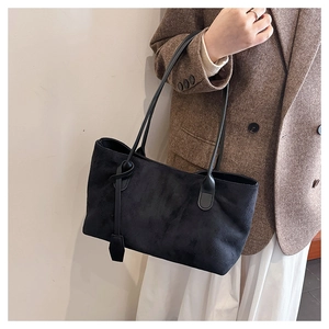 Detail of black suede tote bag with slim shoulder straps worn with a plaid blazer