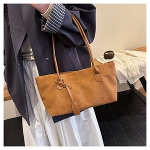 Detail view of a caramel brown suede tote bag featuring slim leather shoulder straps