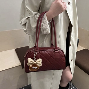 Burgundy quilted tote bag with bow charm, styled with a beige trench coat for 2025 fashion