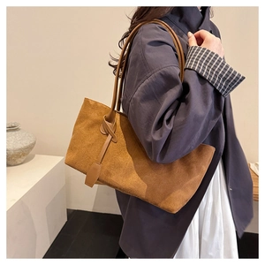 Detail of caramel suede tote bag featuring a decorative knot on the shoulder strap