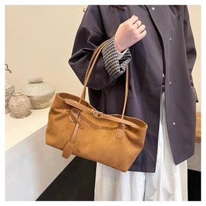 Close-up of vintage brown suede tote bag featuring slim leather handles and buckle detail