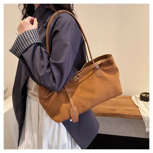 Detail of brown matte suede tote bag showing its slouchy trapezoid shape and side tassels