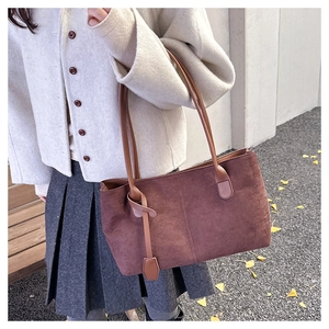 Close-up of brown suede tote bag featuring slim shoulder straps and minimalist tassel detail