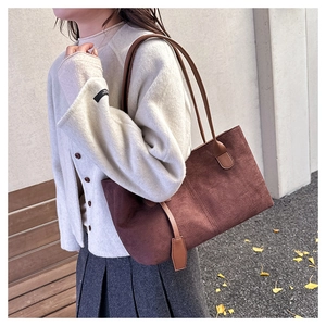 Detail of soft dark brown suede tote bag with slim shoulder handles in autumn scene