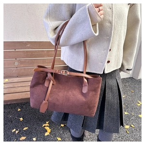 Detailed view of brown suede tote bag featuring fine stitching and vintage metal buckle strap