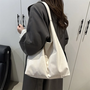 Minimalist beige leather tote bag with wide strap worn by model in a modern interior