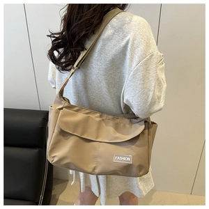 Close-up of khaki nylon messenger bag with adjustable strap and fashion label detail