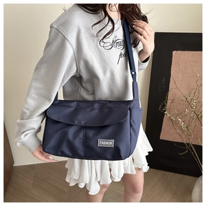 Detail of navy blue waterproof nylon messenger bag with adjustable strap and fashion label