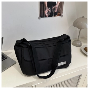 Détail du sac cabas en toile noire avec étiquette mode et bandoulière réglable