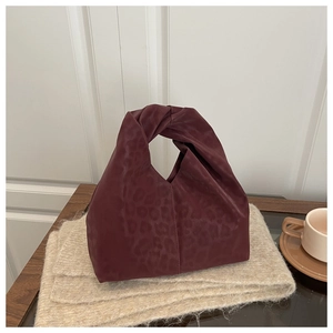 Detail of burgundy leopard print tote bag with stylish knotted handle on a wooden desk
