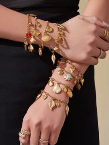 Close-up of gold-plated ocean-themed charms and layered bracelets with shell accents